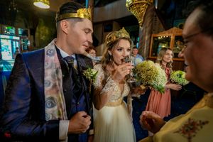 A couple participates in a traditional Orthodox Christian wedding ceremony with priests in golden robes.