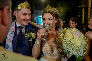 Wedding celebration moment in ornate church with floral bouquets and formal attire.