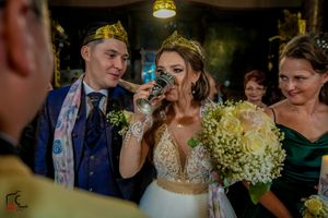 Wedding ceremony participants gathered near altar in decorated Orthodox church.