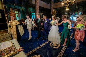Wedding guests gathered in an Orthodox church with blue carpet and golden decorations.