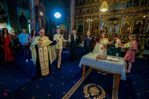 Orthodox church interior with ornate altar and religious icons during wedding ceremony.