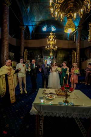 Religious wedding ceremony in progress inside an Orthodox church with elaborate golden decor.