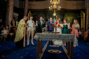 Formal event in a grand ballroom with ornate decor and multiple chandeliers overhead.