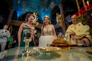 Elegant wedding reception table setup with golden candlesticks and desserts under blue ambient lighting.