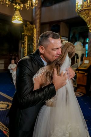 Emotional dance moment during wedding reception under golden chandelier lighting.