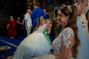 Elegant wedding reception with flower girls in white and green dresses dancing on ornate blue carpet.