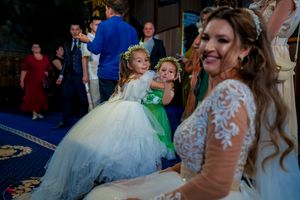 Wedding reception scene showing flower girls in tulle dresses dancing on blue carpet.