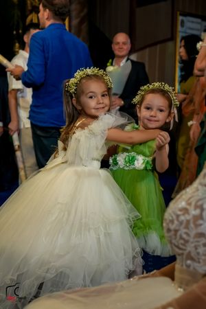 Two flower girls in contrasting white and green dresses dance together at an elegant reception.