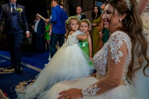 Wedding reception scene with flower girls in white and green dresses on blue carpeted floor.