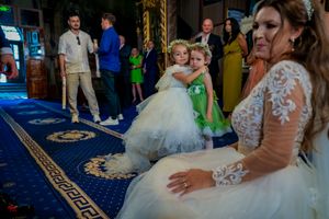 Wedding reception scene on blue carpet with flower girls in white and green dresses.