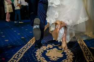 Close-up of wedding shoes during a dance on a decorative blue and gold patterned carpet.