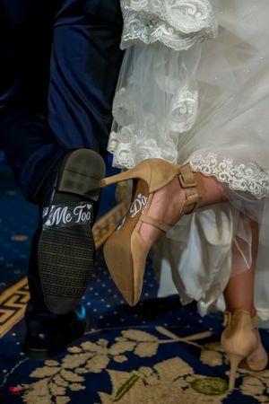 Wedding shoes showing 'Me Too' written on the sole during a dance on an ornate blue carpet.
