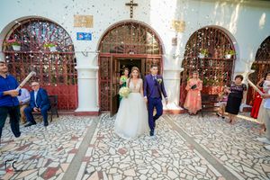 Wedding party gathered in a traditional church courtyard with decorative stonework.