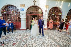 Wedding celebration with confetti toss in an ornate church passageway.