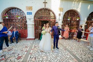 Joyful wedding celebration with confetti in a historic church courtyard.