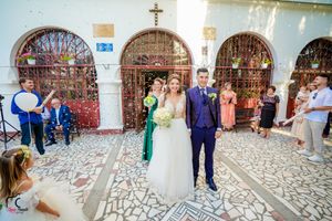 Guests throwing confetti in an ornate church courtyard with patterned stone floor.