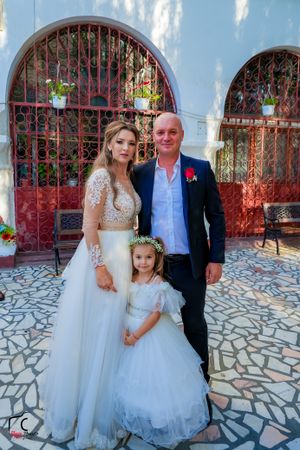Wedding portraits taken against blue walls and red iron gates on stone pavement.