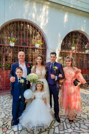 Wedding party members pose with balloons and flowers outside a church entrance.