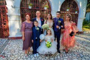 Wedding party members gather for group photos outside a church with distinctive architecture.