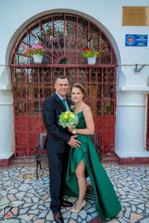 Formal portrait with green dress against Spanish colonial architecture and iron gates.