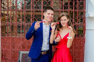 Formal couple taking playful poses in front of Spanish colonial architecture.