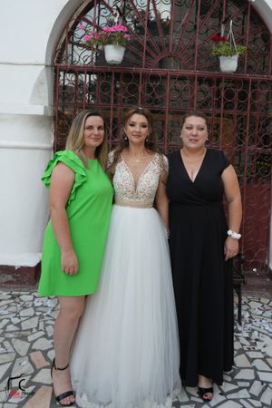 Wedding party posing in front of decorative iron gate wearing formal attire.