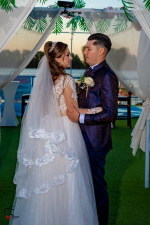 Intimate wedding moment captured under a palm leaf decorated arch at dusk.