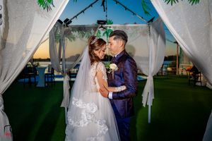 Romantic moment captured under a decorated wedding canopy with white draping.