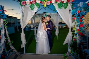 Wedding ceremony setup with floral decorations and white draping in an outdoor venue.