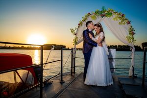 Intimate wedding moment captured on dock with sunset and water backdrop.