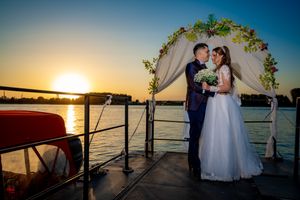 Sunset wedding portrait on dock with floral arch and water views.
