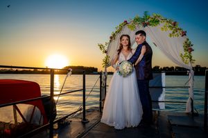 Sunset boat deck wedding ceremony with floral arch and water views.