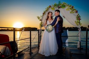 A romantic sunset wedding portrait on a boat deck with water views.