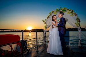 Sunset wedding ceremony by the water with decorated arch and coastal views.