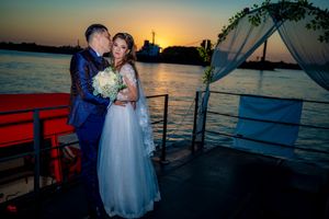 Sunset wedding photography on boat deck with white draped arch and water views.