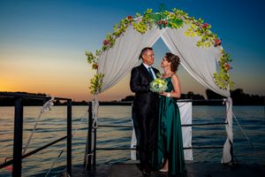 Lakeside wedding ceremony site with white fabric pavilion and floral arrangements.