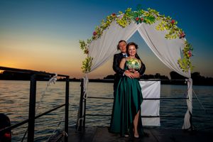 Wedding ceremony setup on dock with white fabric arch and floral accents overlooking water.