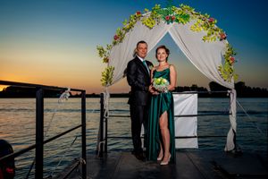 Waterfront wedding ceremony at sunset with decorated arch and ocean backdrop.