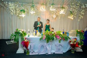 Elegant wedding reception setup with floral arrangements, white decor and ambient lighting.