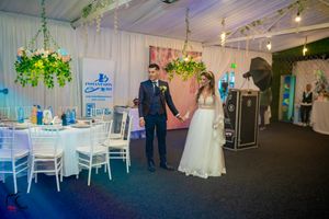 Wedding reception space featuring hanging greenery, white chairs and elegant decor.