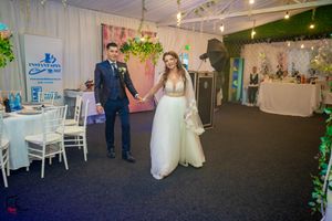 Indoor wedding venue decorated with greenery and white chairs set up for a celebration.