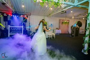 Wedding reception venue with fog effects and colored lighting creating a magical atmosphere.