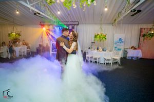 Fog effects create a dreamy atmosphere on a wedding dance floor with blue and purple lighting.