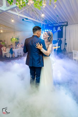 Elegant wedding venue with white decor and atmospheric fog during a romantic dance moment.
