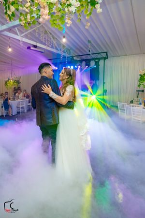 Wedding dance captured in a cloud of fog with vibrant multicolored lighting effects.
