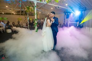 Wedding dance floor illuminated with blue spotlights and atmospheric fog effects.