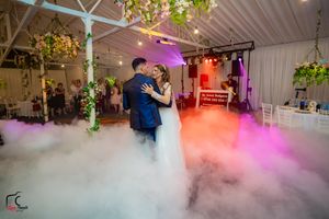 Indoor wedding celebration with colorful lighting and smoke effects creating a dreamlike atmosphere.