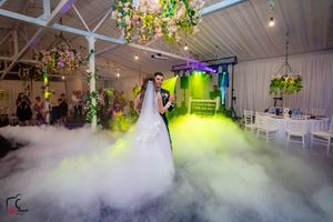 Wedding reception venue with dramatic fog effects and multicolored lighting creating a magical atmosphere.