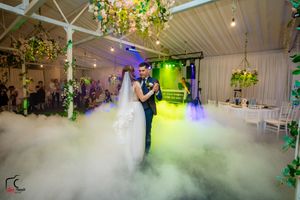 Romantic dance scene with low-lying fog and vibrant lighting effects in an indoor wedding venue.