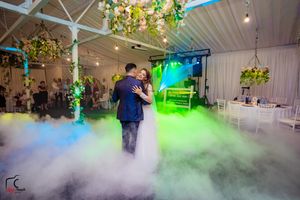 Wedding dance floor filled with atmospheric fog and green lighting effects in an elegant white venue.